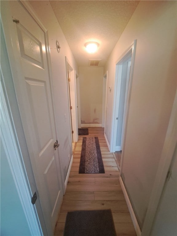 1002 Baltimore Ave, Waycross, GA 31501 - hallway featuring light wood finished floors, baseboards, and a textured ceiling