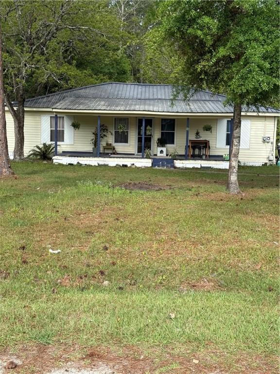 view of front facade with a front lawn, metal roof, and a porch
