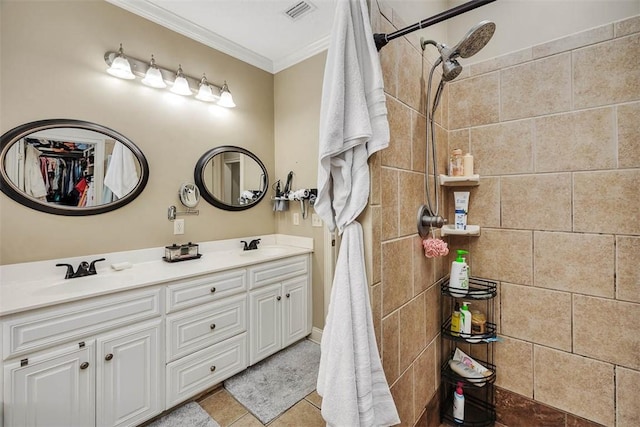 full bath featuring crown molding, double vanity, visible vents, a tile shower, and a sink