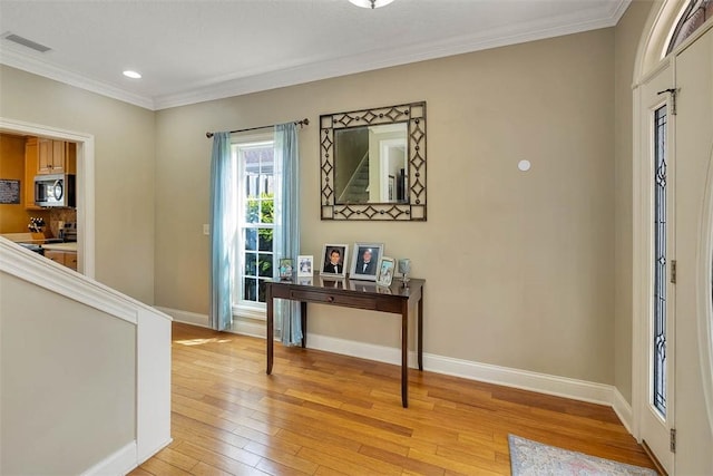 entryway featuring light wood-style floors, visible vents, ornamental molding, and baseboards