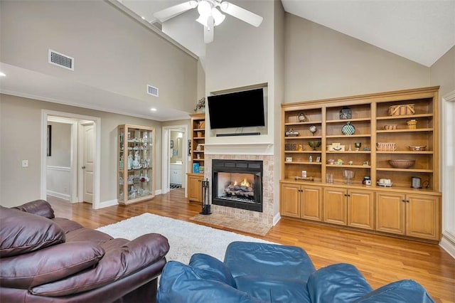 living area with visible vents, light wood-style flooring, and a tiled fireplace