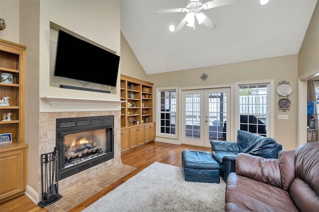 living room featuring vaulted ceiling, french doors, a fireplace, and wood finished floors