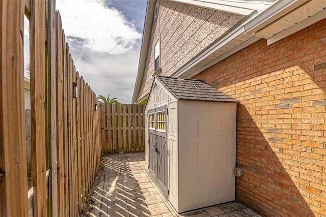 view of property exterior featuring an outbuilding, a storage shed, brick siding, and a fenced backyard