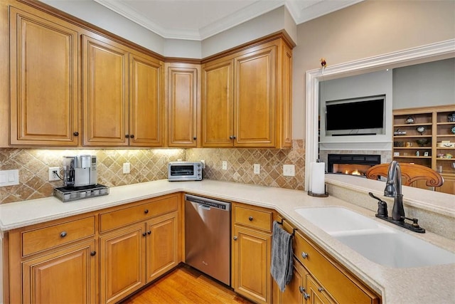 kitchen with ornamental molding, stainless steel dishwasher, a sink, and light wood-style floors