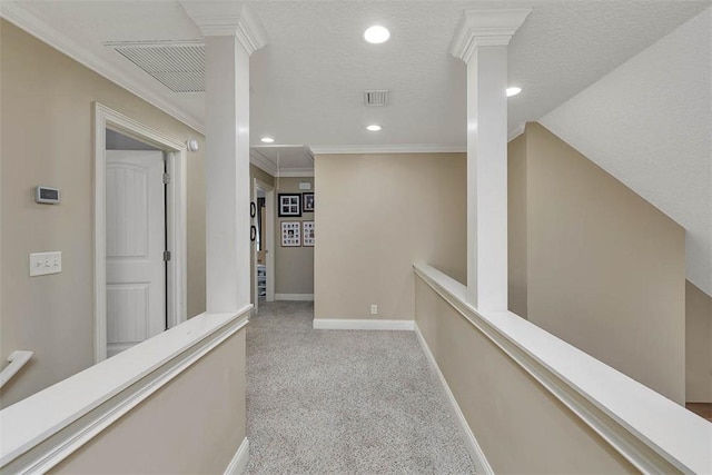 corridor featuring crown molding, visible vents, attic access, carpet flooring, and baseboards