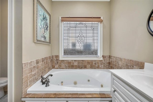 bathroom with a tub with jets, vanity, and toilet