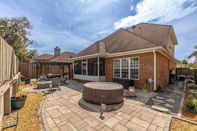 rear view of property with an outdoor fire pit, a fenced backyard, brick siding, a sunroom, and a patio area