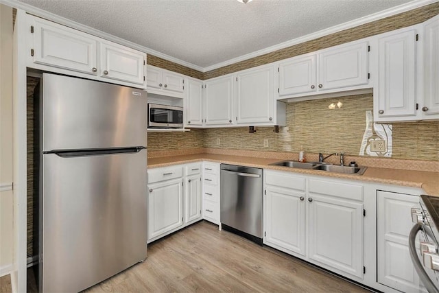 239 Georgia St, Saint Simons Island, GA 31522 - kitchen featuring stainless steel appliances, white cabinetry, light countertops, light wood-style floors, and a textured ceiling
