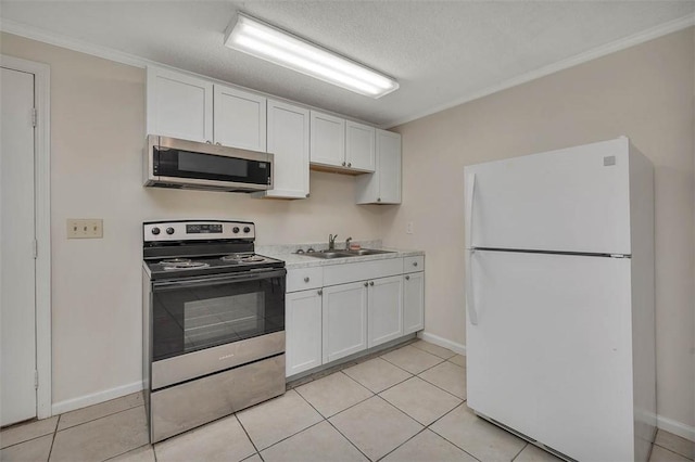 239 Georgia St, Saint Simons Island, GA 31522 - kitchen with stainless steel appliances, white cabinets, crown molding, light countertops, and light tile patterned floors