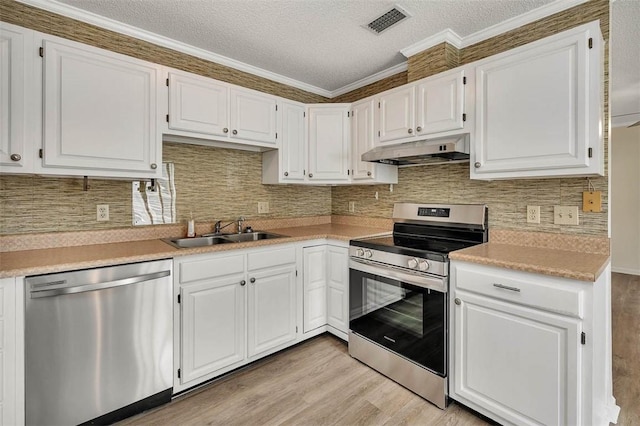 239 Georgia St, Saint Simons Island, GA 31522 - kitchen with appliances with stainless steel finishes, under cabinet range hood, light wood finished floors, white cabinetry, and ornamental molding