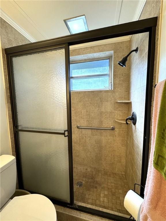 bathroom featuring crown molding, an enclosed shower, and toilet