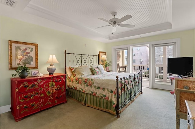 carpeted bedroom with ceiling fan, a tray ceiling, and access to outside