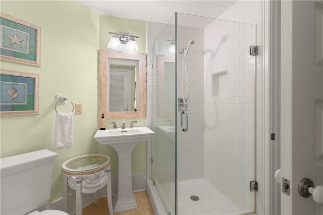 bathroom featuring sink, toilet, and a shower with door