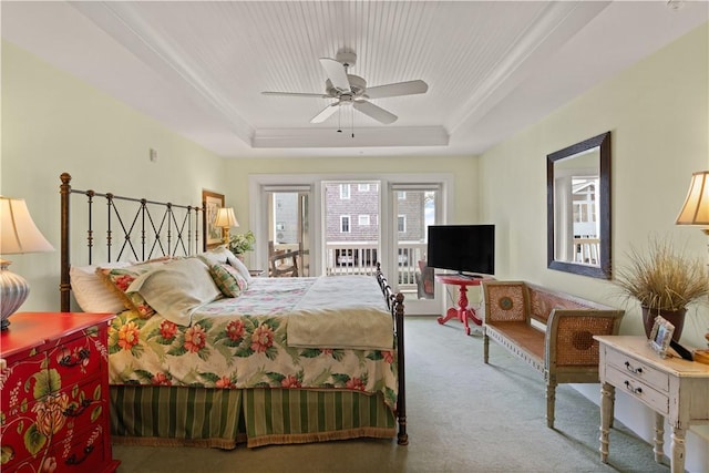 carpeted bedroom featuring ceiling fan, a raised ceiling, and access to outside