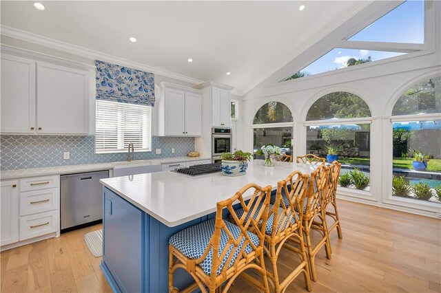 122 Saint Andrews Dr, Saint Simons Island, GA 31522 - kitchen featuring appliances with stainless steel finishes, a center island, light countertops, a breakfast bar area, and ornamental molding
