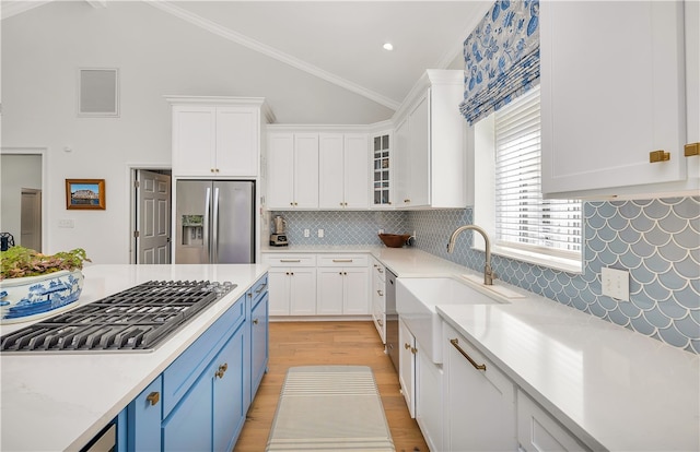 122 Saint Andrews Dr, Saint Simons Island, GA 31522 - kitchen with stainless steel appliances, blue cabinetry, light countertops, white cabinetry, and light wood-type flooring