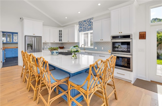 122 Saint Andrews Dr, Saint Simons Island, GA 31522 - kitchen with appliances with stainless steel finishes, a large island, white cabinetry, light wood-style flooring, and lofted ceiling