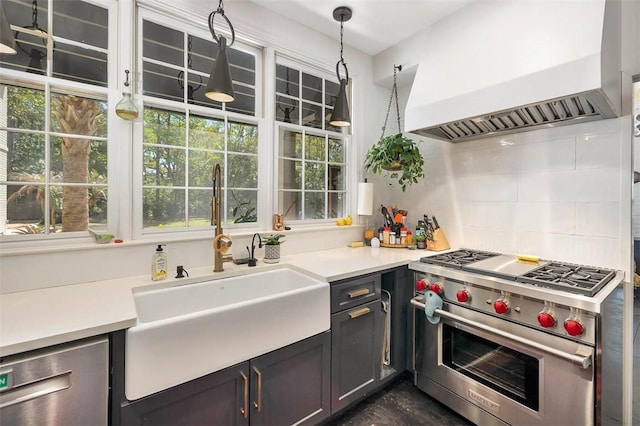 kitchen featuring light countertops, custom range hood, decorative backsplash, appliances with stainless steel finishes, and a sink