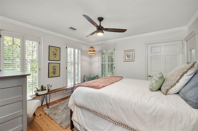 bedroom with visible vents, light wood-style flooring, crown molding, and multiple windows