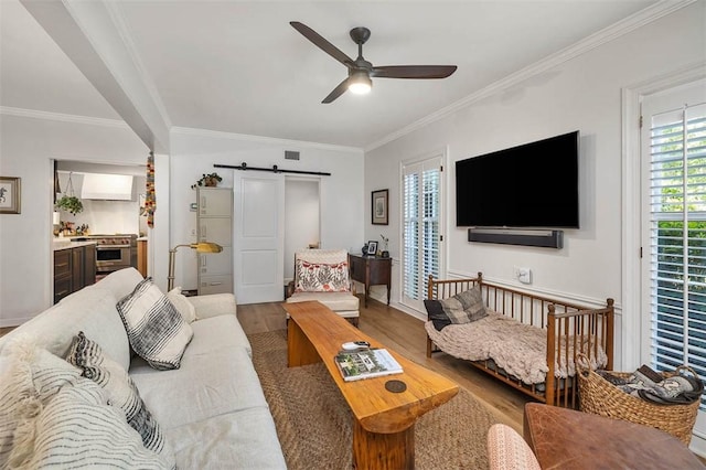 living area featuring visible vents, a ceiling fan, a barn door, and wood finished floors