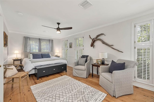 bedroom featuring light wood finished floors, visible vents, and ornamental molding