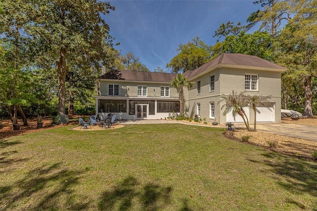 back of house featuring an attached garage, concrete driveway, a yard, and a patio