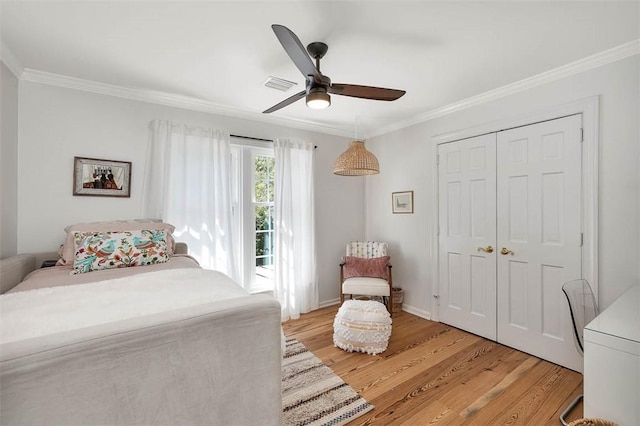 bedroom featuring a closet, visible vents, light wood-type flooring, and ornamental molding