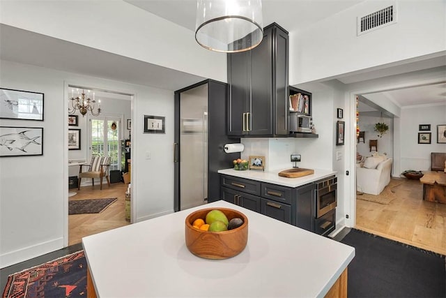 kitchen featuring visible vents, wood finished floors, stainless steel microwave, and light countertops