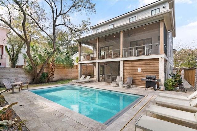 rear view of property featuring a fenced in pool, a sunroom, a patio, and a balcony