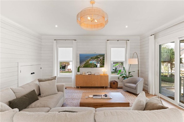 living room featuring crown molding, a healthy amount of sunlight, a chandelier, and light hardwood / wood-style floors