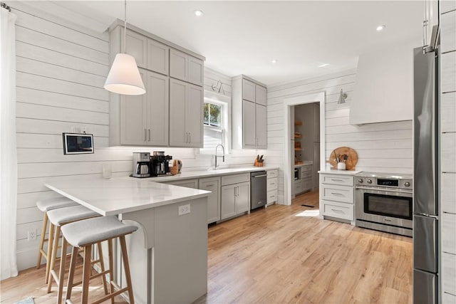 kitchen featuring a breakfast bar, sink, gray cabinetry, hanging light fixtures, and kitchen peninsula