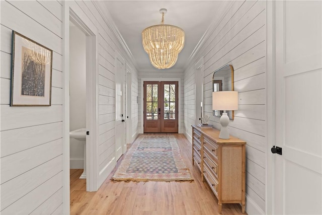 entryway with crown molding, an inviting chandelier, french doors, and light hardwood / wood-style flooring