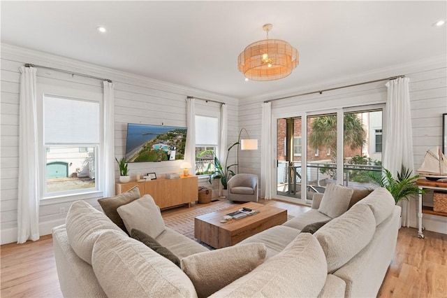 living room featuring ornamental molding, wooden walls, and light hardwood / wood-style floors