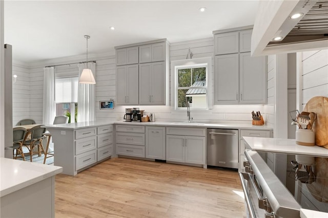 kitchen featuring sink, hanging light fixtures, light wood-type flooring, stainless steel dishwasher, and kitchen peninsula