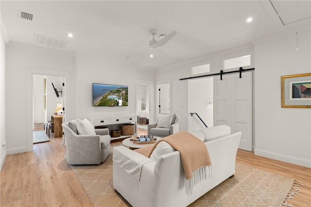 living room featuring crown molding, ceiling fan, a barn door, and light hardwood / wood-style flooring