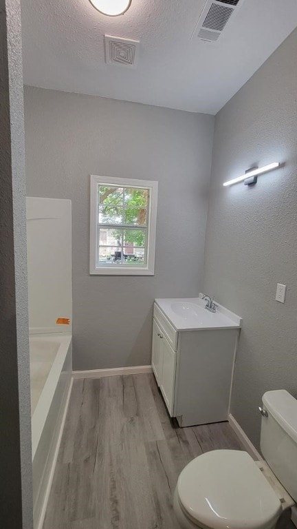 506 Ware St, Waycross, GA 31501 - bathroom featuring wood finished floors, vanity, a bath, and a textured ceiling