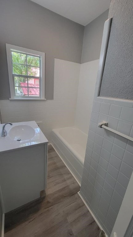 506 Ware St, Waycross, GA 31501 - full bathroom with tile walls, wood finished floors, a tub, vanity, and wainscoting