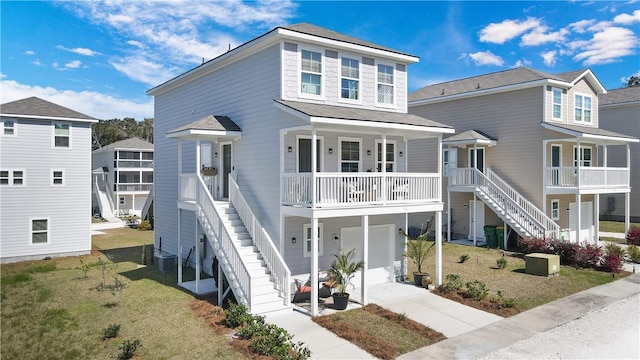 beach home with a front lawn, stairway, an attached garage, and covered porch