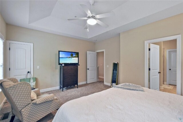 bedroom with a tray ceiling, ceiling fan, and light carpet