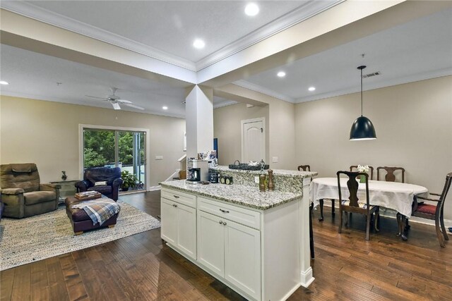 kitchen featuring pendant lighting, dark wood-type flooring, white cabinets, ceiling fan, and light stone counters