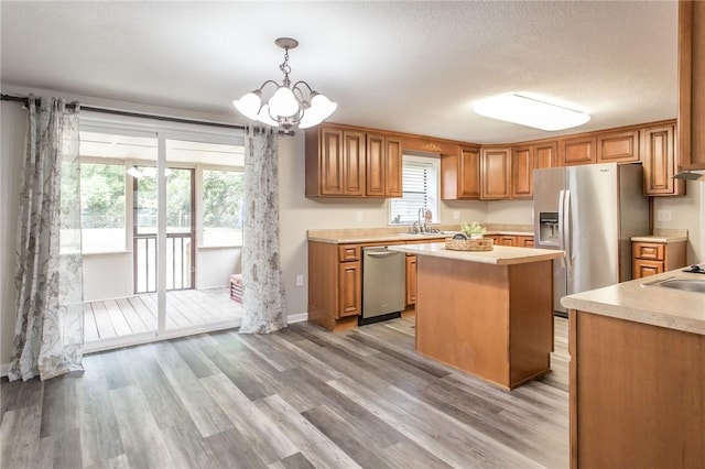 1348 Crestridge Rd, Waycross, GA 31503 - kitchen featuring appliances with stainless steel finishes, light countertops, a center island, light wood-style flooring, and a textured ceiling