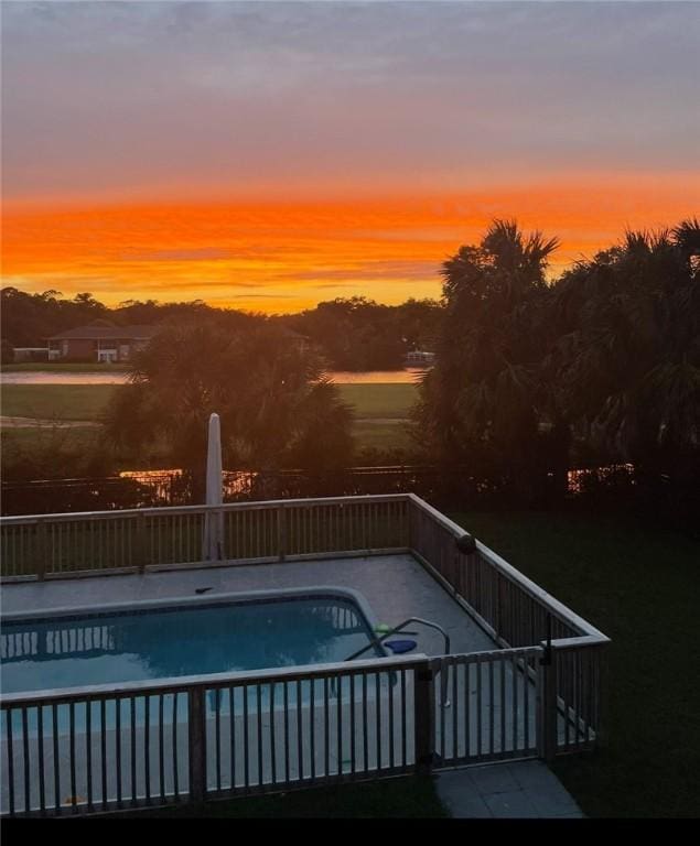 pool at dusk featuring a fenced in pool