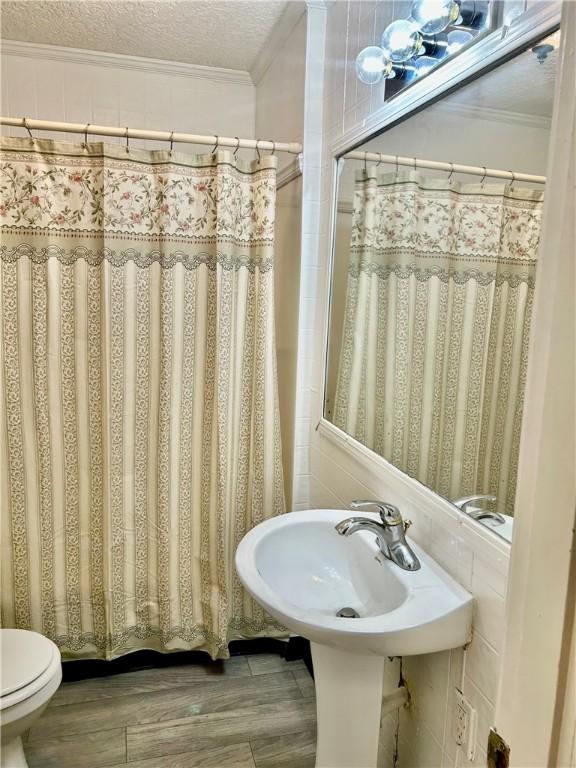 1110 Waller St, Waycross, GA 31501 - full bathroom with wood finished floors, a textured ceiling, ornamental molding, and toilet