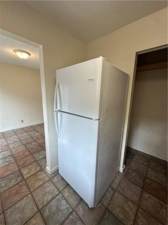 kitchen featuring stone finish floor, baseboards, and freestanding refrigerator