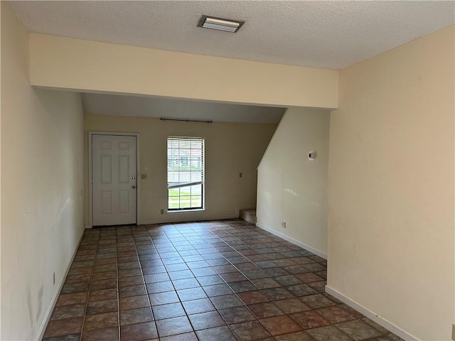 interior space featuring a textured ceiling, baseboards, and visible vents