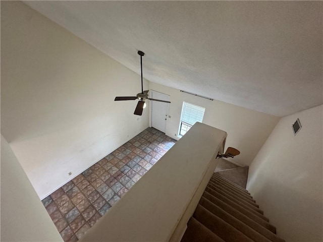 staircase with ceiling fan, a textured ceiling, tile patterned floors, lofted ceiling, and visible vents