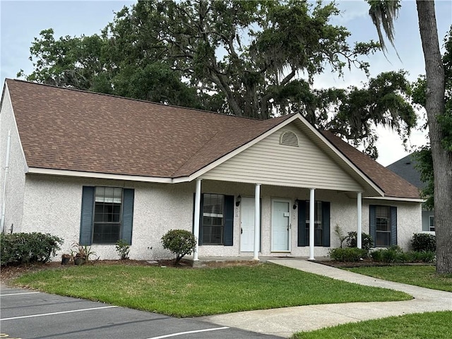 view of front of house featuring a shingled roof, a front lawn, and stucco siding