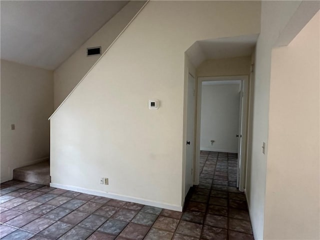empty room featuring stone tile floors, baseboards, and visible vents