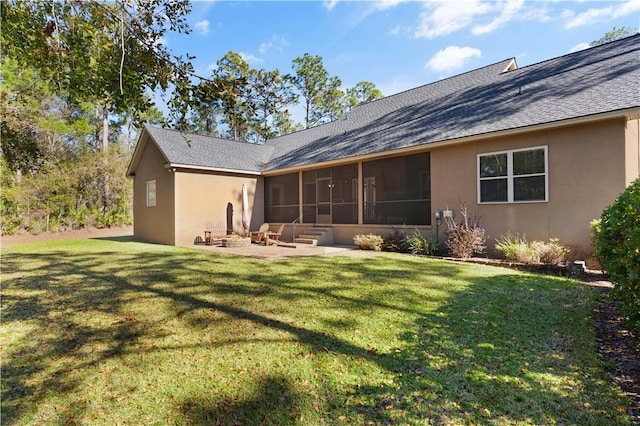 rear view of house with a sunroom, a patio area, an outdoor fire pit, and a yard