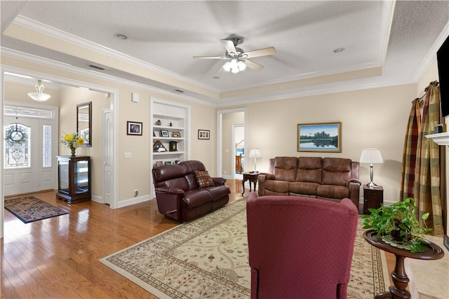 living room with built in shelves, hardwood / wood-style floors, a textured ceiling, and crown molding